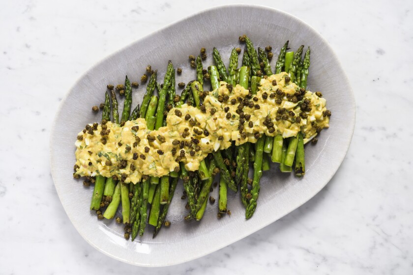 This image released by Milk Street shows a recipe for asparagus covered in Sauce gribiche and fried capers. (Milk Street via AP)