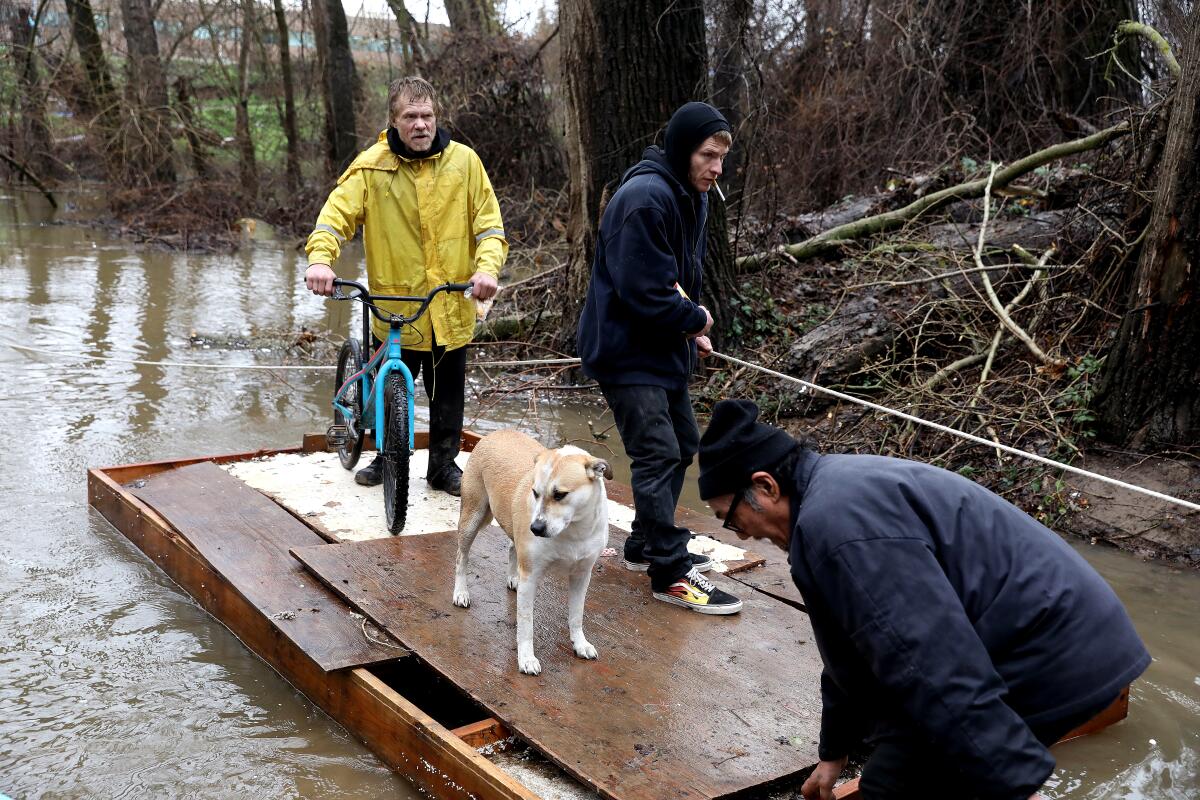 Three men and a dog use a raft to get off a flooded homeless encampment on Bannon Island.
