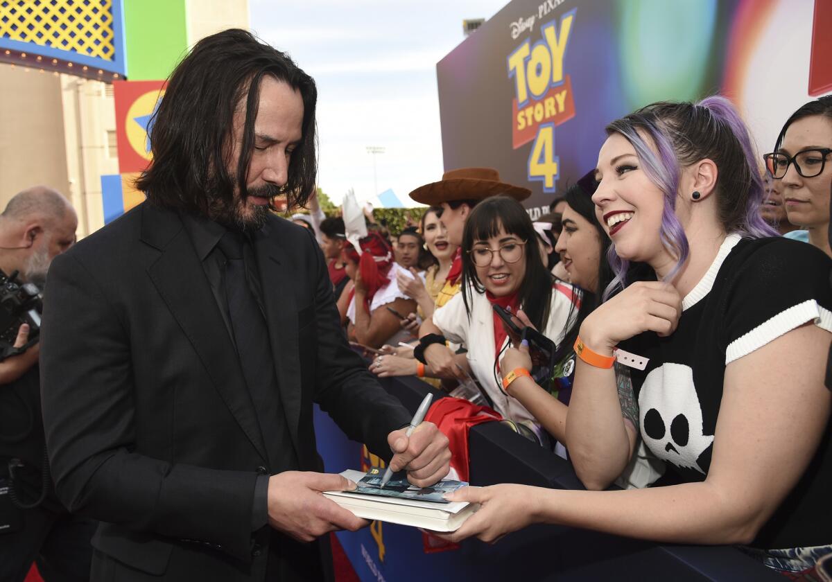 Keanu Reeves signs an autograph at the world premiere of "Toy Story 4."