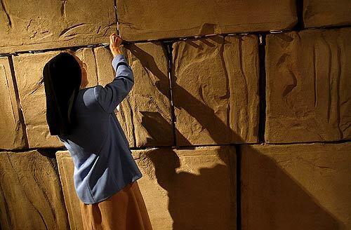 Sister Thomas Bernard MacConnell of the Spirituality Center at Mount St. Mary's College tucks a note into a replica of Jerusalem's Western Wall, which is part of an exhibit at the Skirball Cultural Center in Los Angeles that highlights Pope John Paul II's relationship with Jews.
