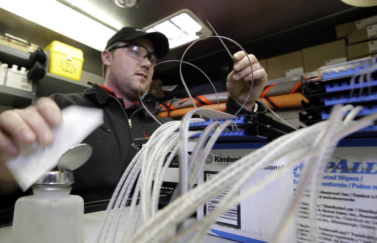 Todd Torbert, a Verizon cable splicing technician, works to connect the glass fibers to the Verizon FiOS fiber network in Rockville, Md., in a photo from 2009.