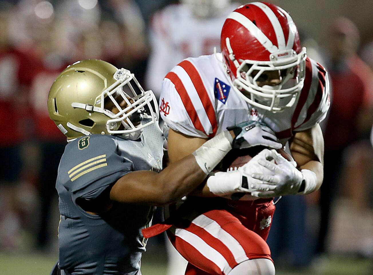 Mater Dei running back London Iakopo breaks through a tackle by Poly defensive back Iman Marshall during a touchdown run in the second quarter Friday night in a Southern Section Pac-5 Division semifinal playoff game at Veterans Stadium in Long Beach.