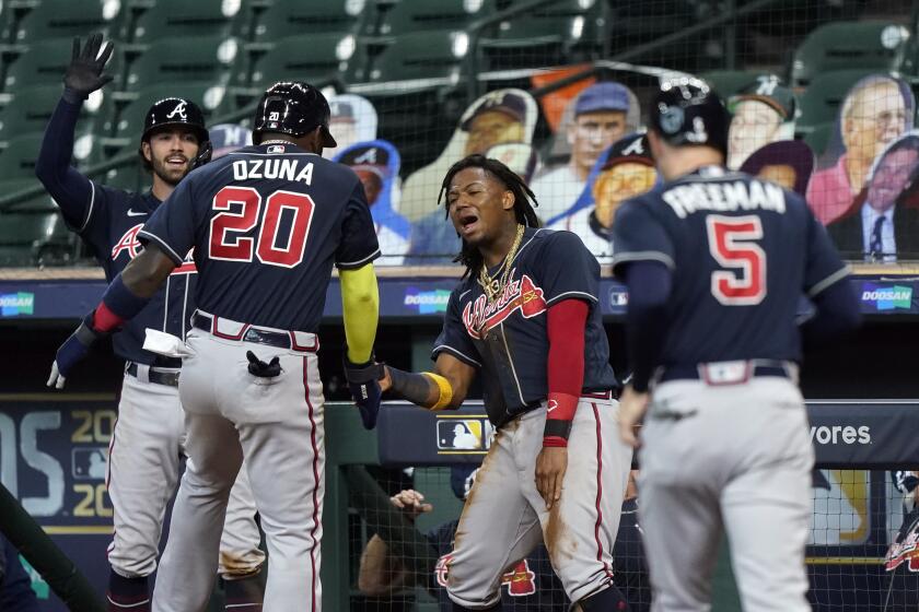 Atlanta Braves' Ronald Acuna Jr., center, and Dansby Swanson, left, congratulate Marcell Ozuna (20) after Ozuna and Freddie Freeman (5) scored in the third inning agains the Miami Marlins in Game 3 of a baseball National League Division Series, Thursday, Oct. 8, 2020, in Houston. (AP Photo/David J. Phillip)