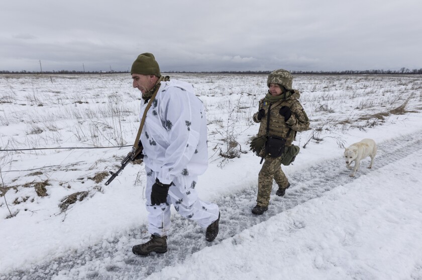 Ukrainian soldiers walk at the line of separation from pro-Russian rebels, Donetsk region, Ukraine, Sunday, Jan. 2, 2022. President Joe Biden has warned Russia's Vladimir Putin that the U.S. could impose new sanctions against Russia if it takes further military action against Ukraine. (AP Photo/Andriy Dubchak)