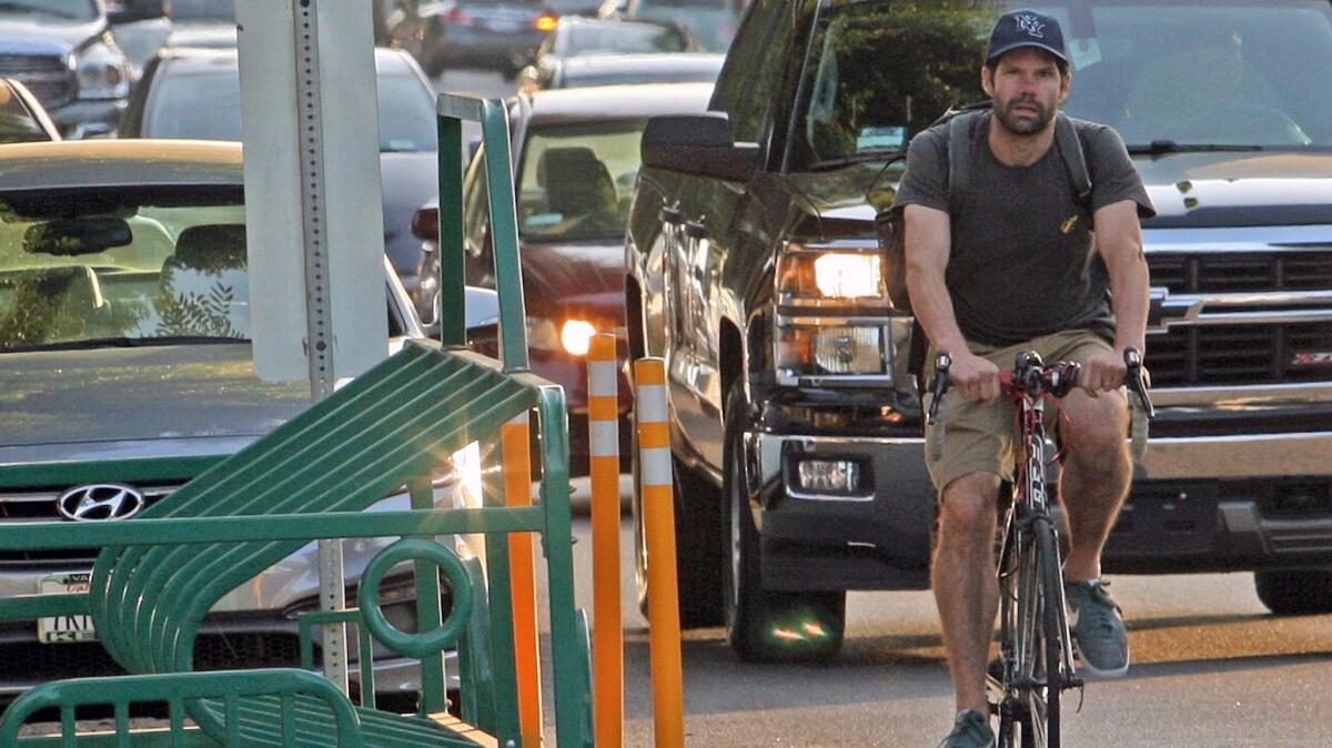 A bicyclist rides by a bike corral in front of Tony's Darts Away.