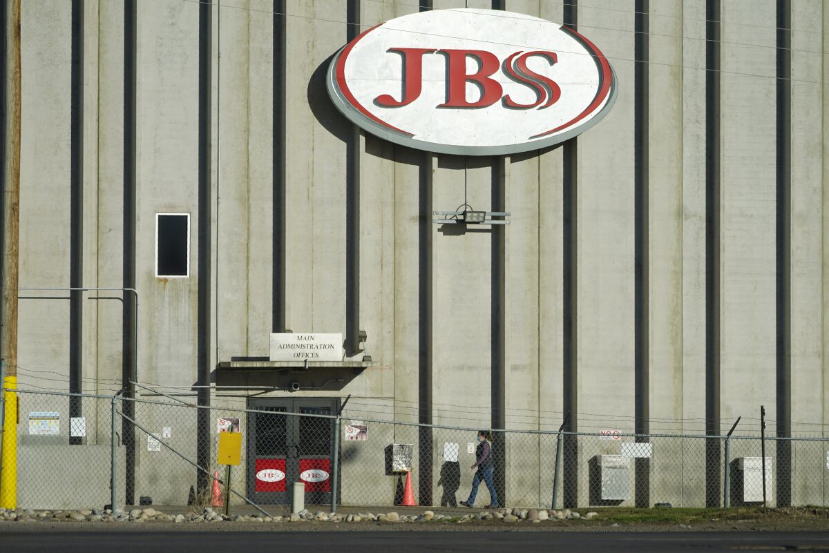 FILE - A worker heads into the JBS meatpacking plant Monday, Oct. 12, 2020, in Greeley, Colo. Meatpacking giant JBS has agreed to a $52.5 million settlement in a beef price-fixing lawsuit, Thursday, Feb. 3, 2022, that some say supports their concerns about how the lack of competition in the industry affects prices. Colorado-based JBS didn’t admit any wrongdoing as part of the settlement and a spokeswoman said the company will continue to defend itself. (AP Photo/David Zalubowski)
