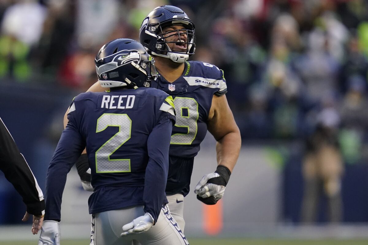 Seattle Seahawks defensive tackle Al Woods, right, reacts with cornerback D.J. Reed (2) after a play against the San Francisco 49ers during the second half of an NFL football game, Sunday, Dec. 5, 2021, in Seattle. (AP Photo/Elaine Thompson)