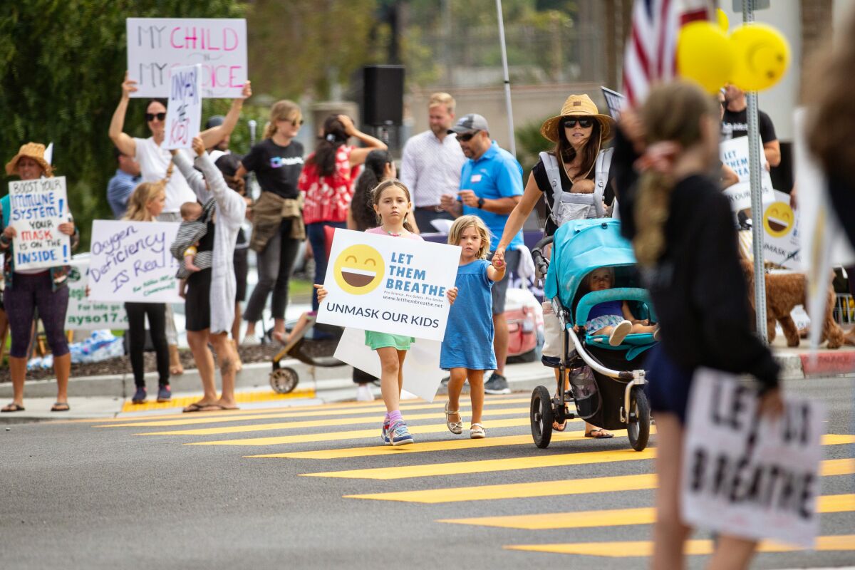 Adults and children carry signs on a street crosswalk.