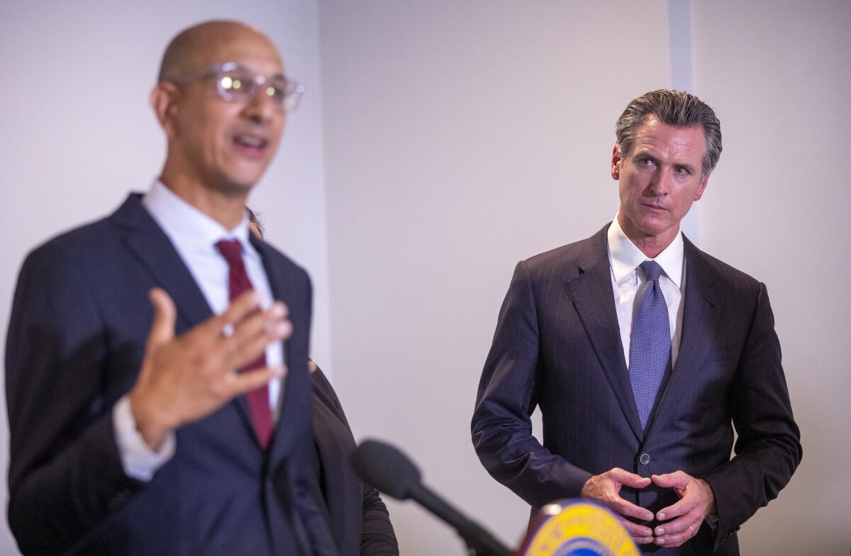 two men in suits, one speaking while the other looks on 