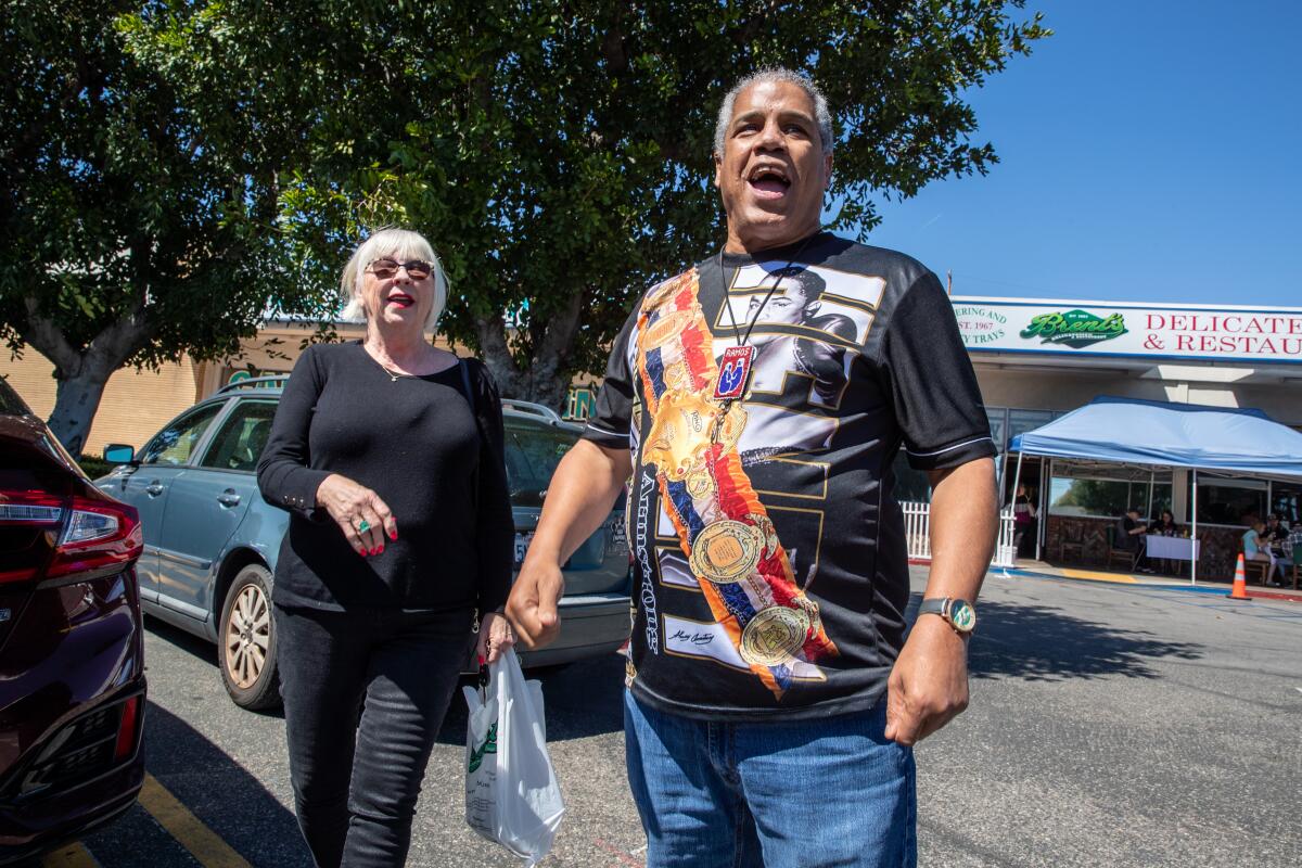 Former boxer Alex Ramos stands outside next to a woman who runs his boxers foundation. 