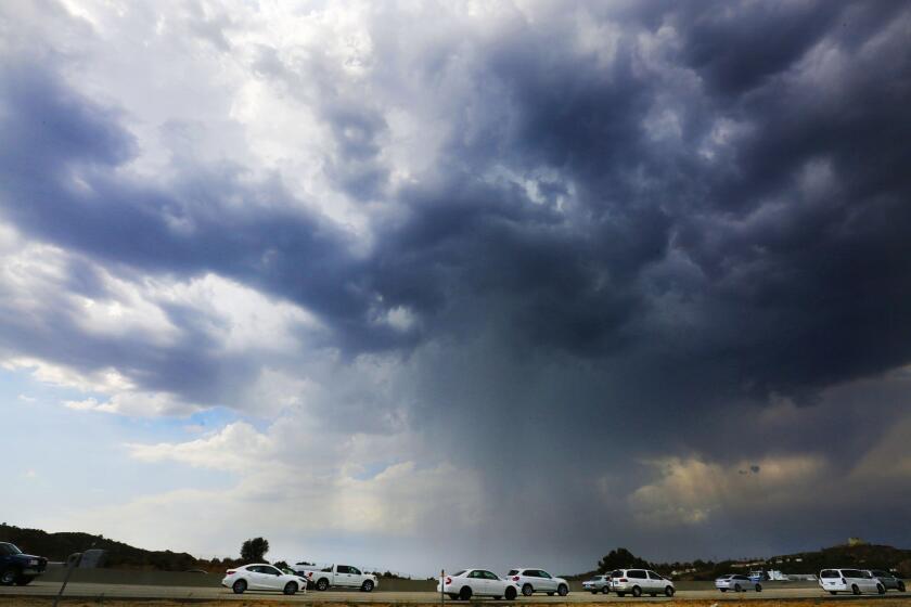 Cars move slowly along the northbound 14 freeway in the Santa Clarita area Wednesday as storm clouds and rain pass over the area.