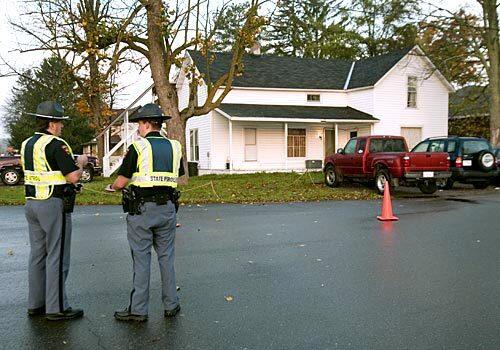 State troopers stand near a house in Crandon, Wis., where an off-duty sheriff's deputy killed six people early Sunday. A seventh victim is in critical condition. The gunman, Tyler Peterson, 20, was shot to death by police officers.