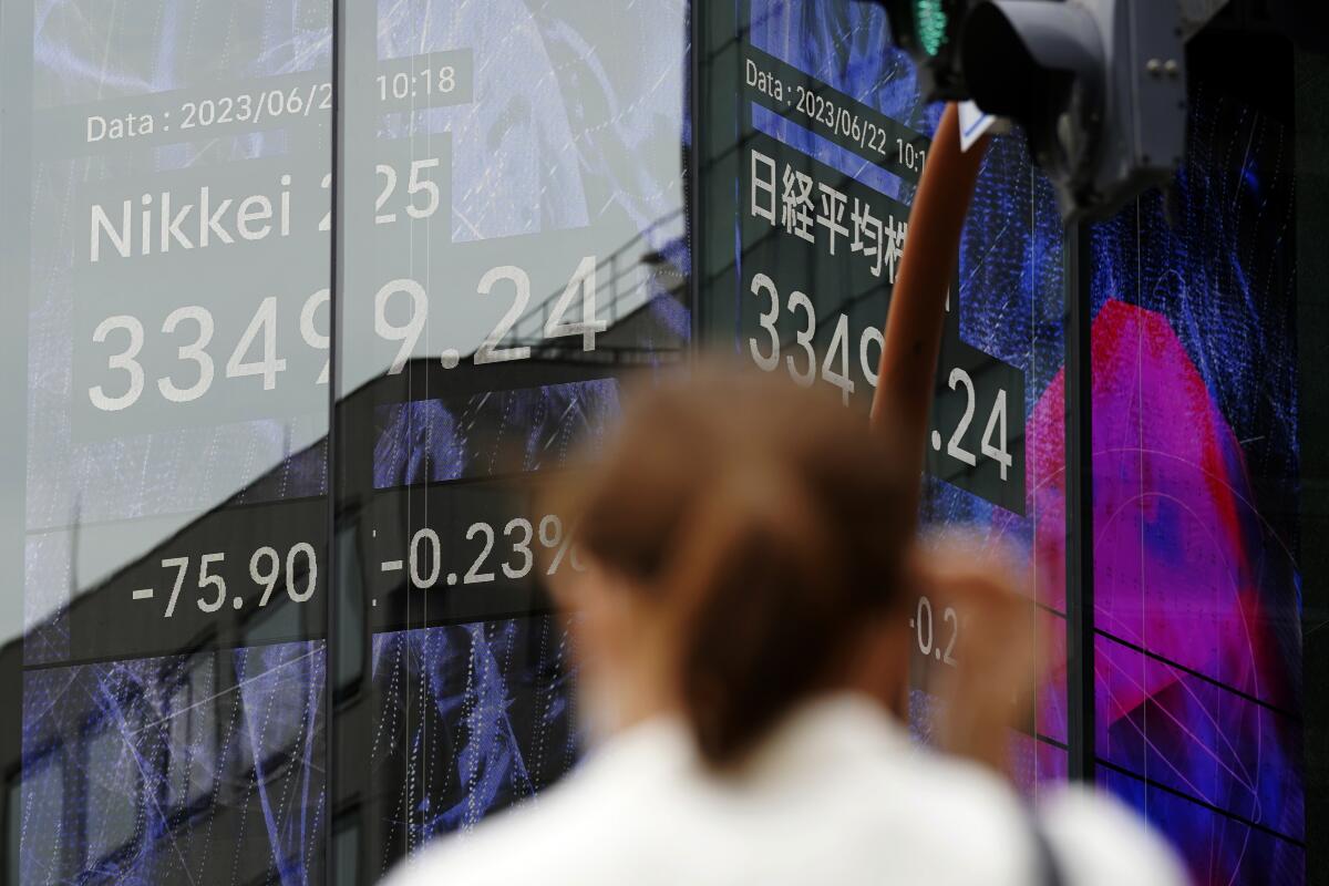 A person stands in front of an electronic stock board showing Japan's Nikkei 225 index at a securities firm.
