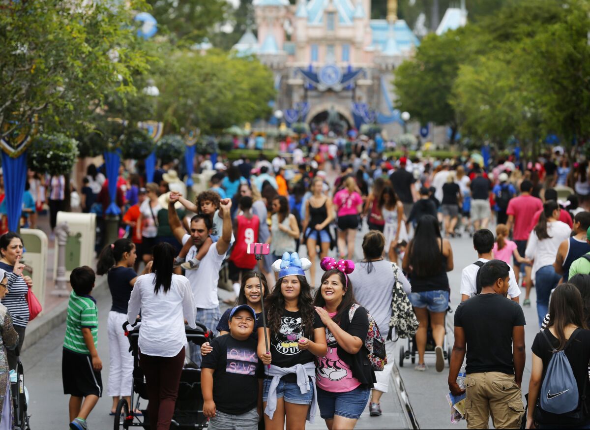 Visitors to Disneyland during its 60th Anniversary Diamond Jubilee use a selfie stick to take a photo on June 10, 2015.