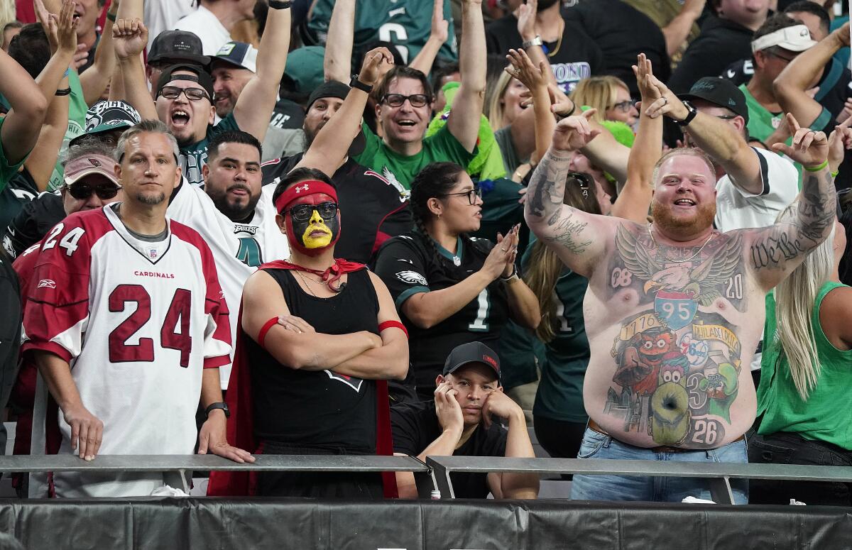 Dejected Arizona Cardinals fans stand next to jubilant Philadelphia Eagles fans.