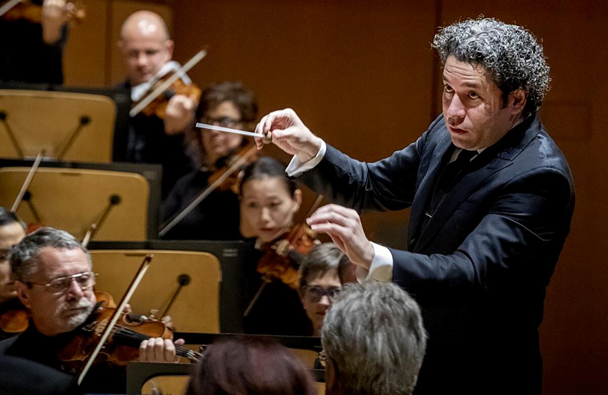 Gustavo Dudamel holds up a baton.