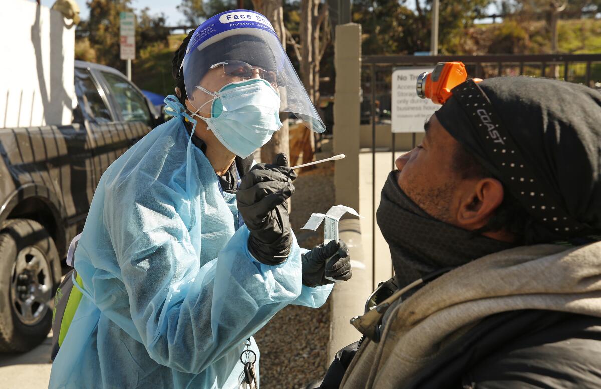 Nurse Leah Edoloverio administers a nasal swab test for COVID-19 to a homeless client named Ace in Inglewood