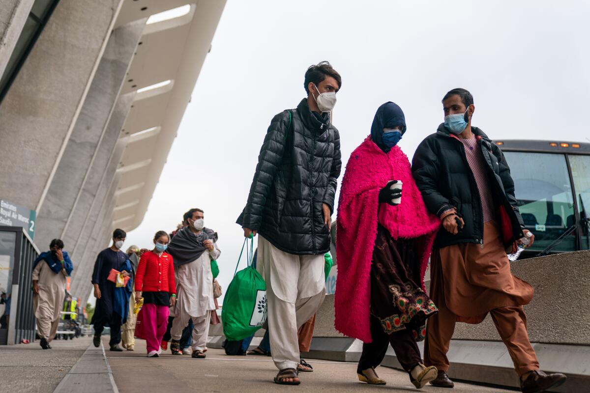Evacuees walk outside an airport building toward buses 