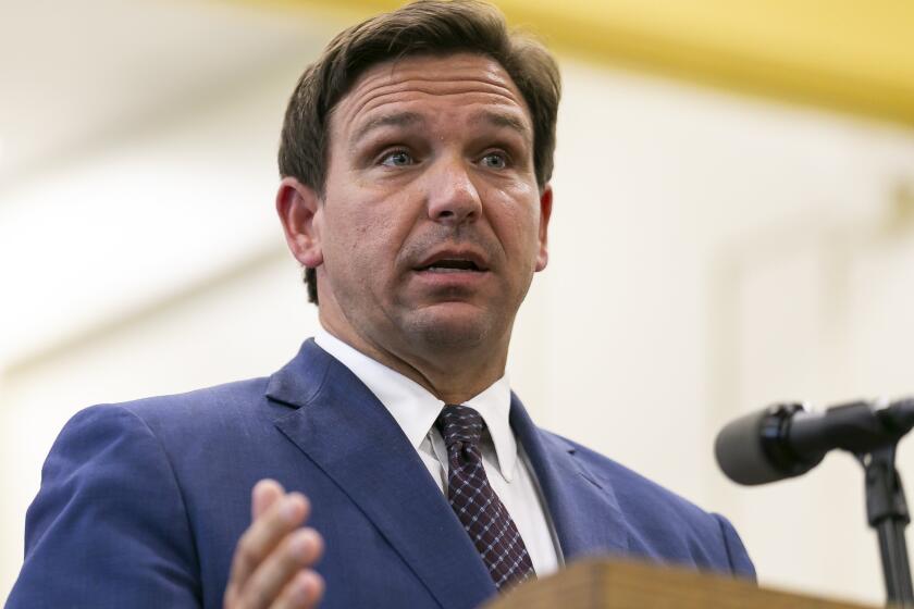 FILE - This May 4 2021 file photo shows Florida Gov. Ron DeSantis, center, speaks during a news conference at West Miami Middle School in Miami. Several states scaled back their reporting of COVID-19 statistics this July 2021, just as cases across the country started to skyrocket, depriving the public of real-time information on outbreaks, cases, hospitalizations and deaths in their communities. (Matias J. Ocner/Miami Herald via AP, File)