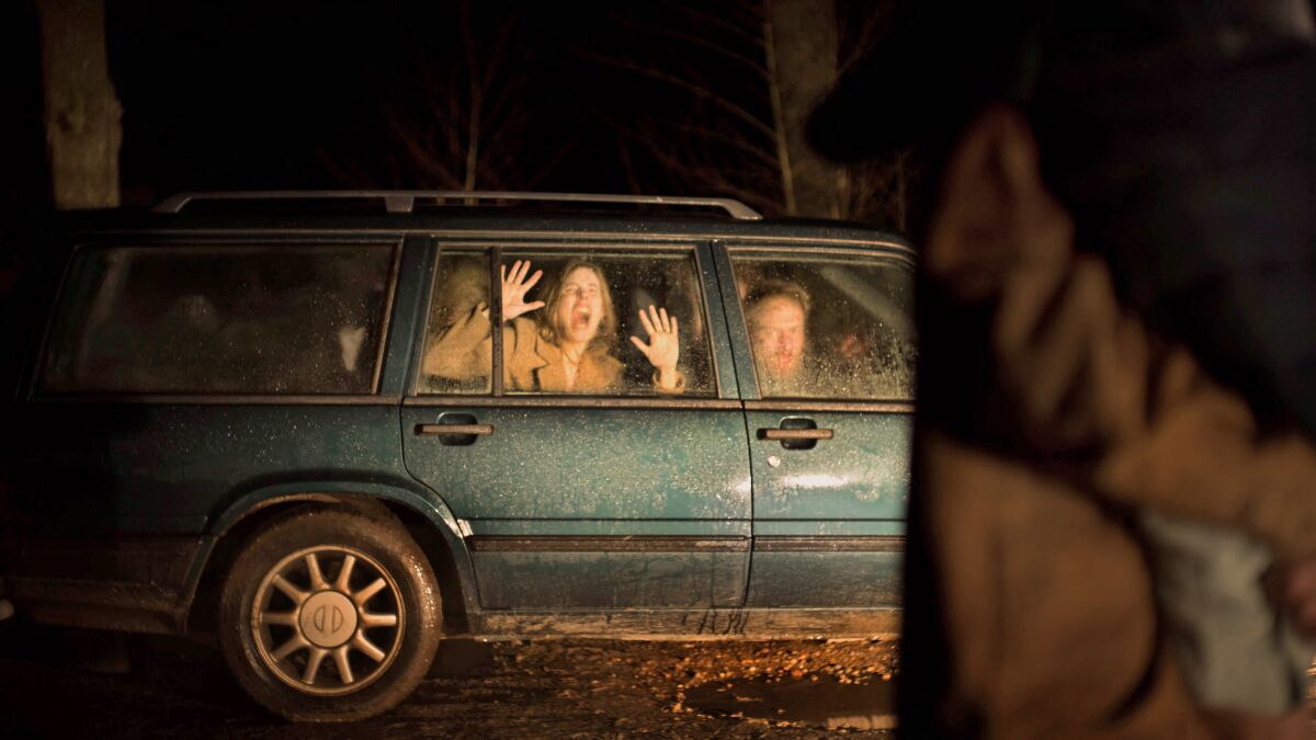 A woman and man screaming from inside a car at night.