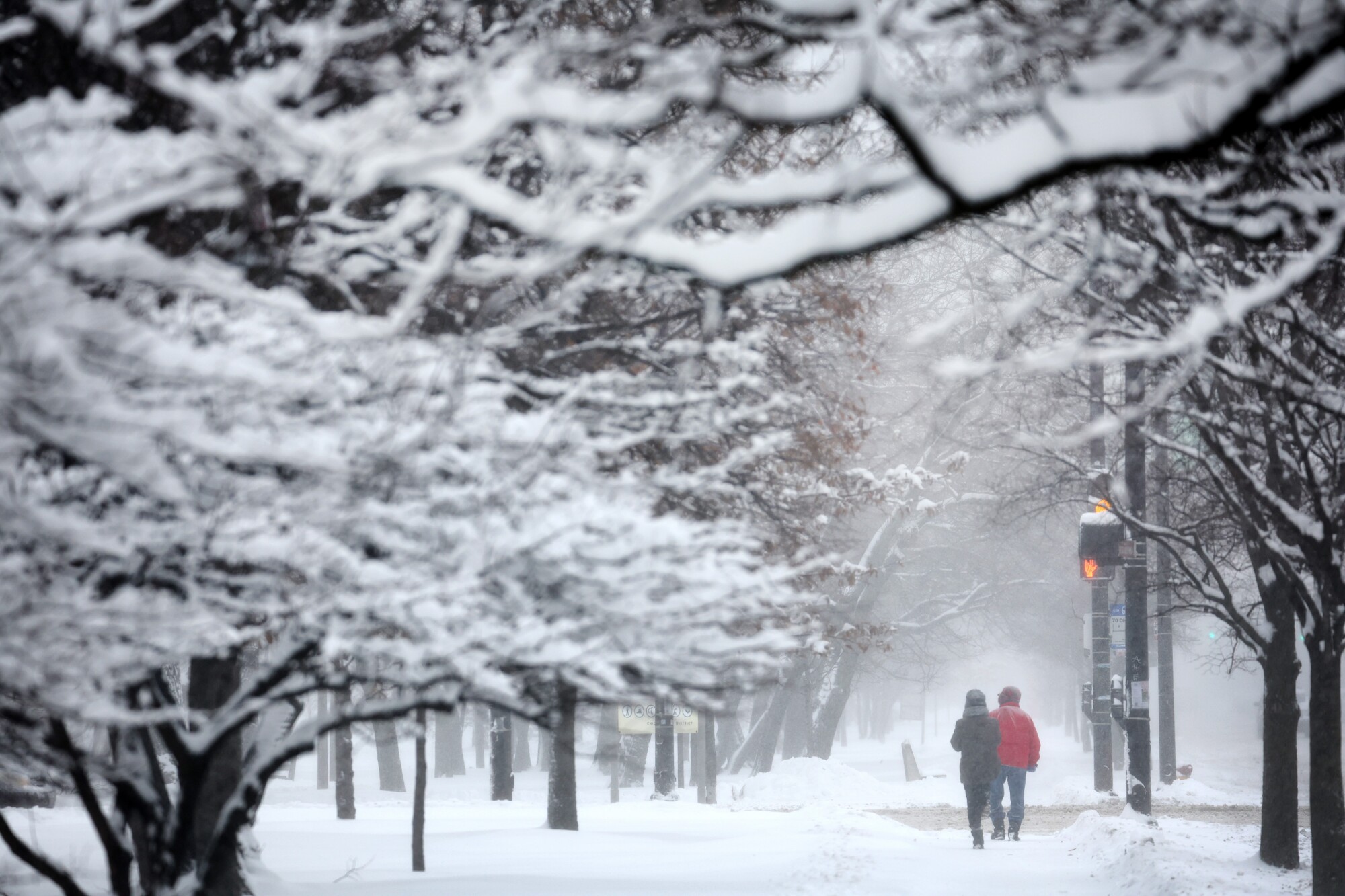 People walk down a snow-covered sidewalk