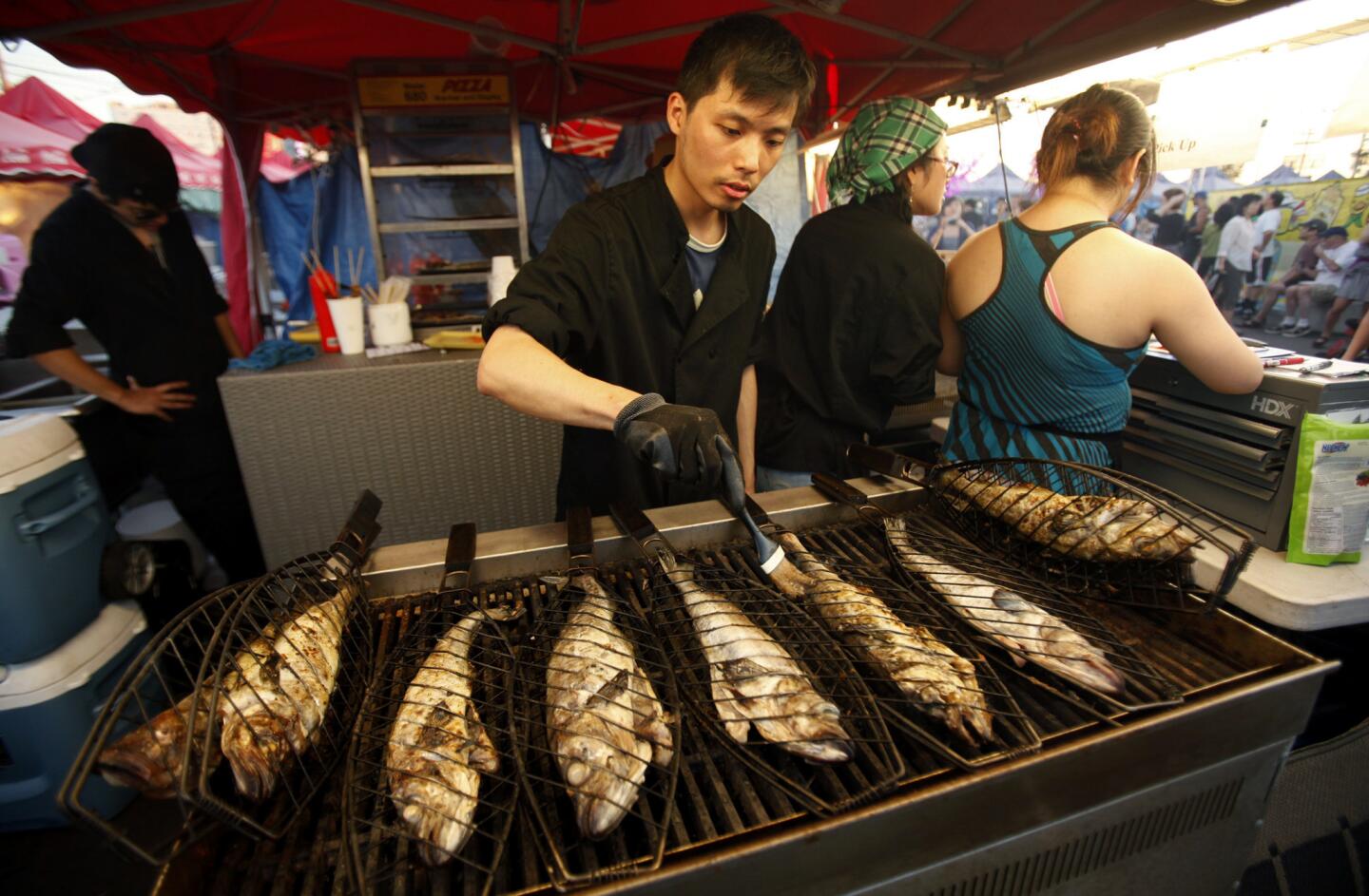 Lewis Chen grills whole fish over open coals, basted with olive oil and butter and doused with red pepper flakes, at Honey's BBQ at the Richmond Night Market. The market features small smokey food booths with everything you could imagine.