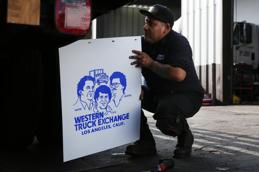 LOS ANGELES, CA-NOVEMBER 6, 2019: Lennyn Del Rio adds the Western Truck Exchange tire flap while working on it at Western Truck Exchange on November 6, 2019, in Los Angeles, California. The business is 92 years old and sells, repairs, insures, licenses and finances trucks. (Photo By Dania Maxwell / Los Angeles Times)