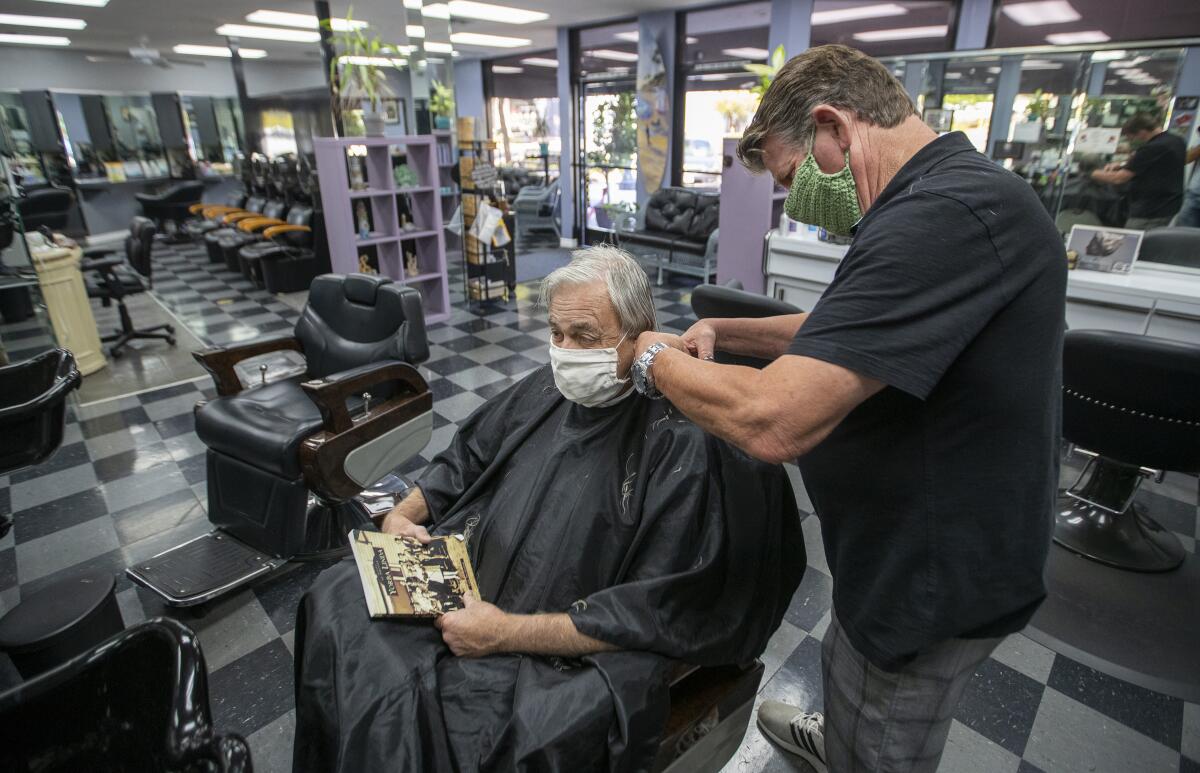 Barber and salon owner Steve Curtis cuts Bill Janeway's hair at Joncolby's Hair Salon on Tuesday in Yorba Linda.
