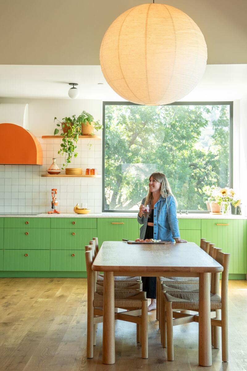 Lindsay Sheron stands at her dining room table inside her kitchen.