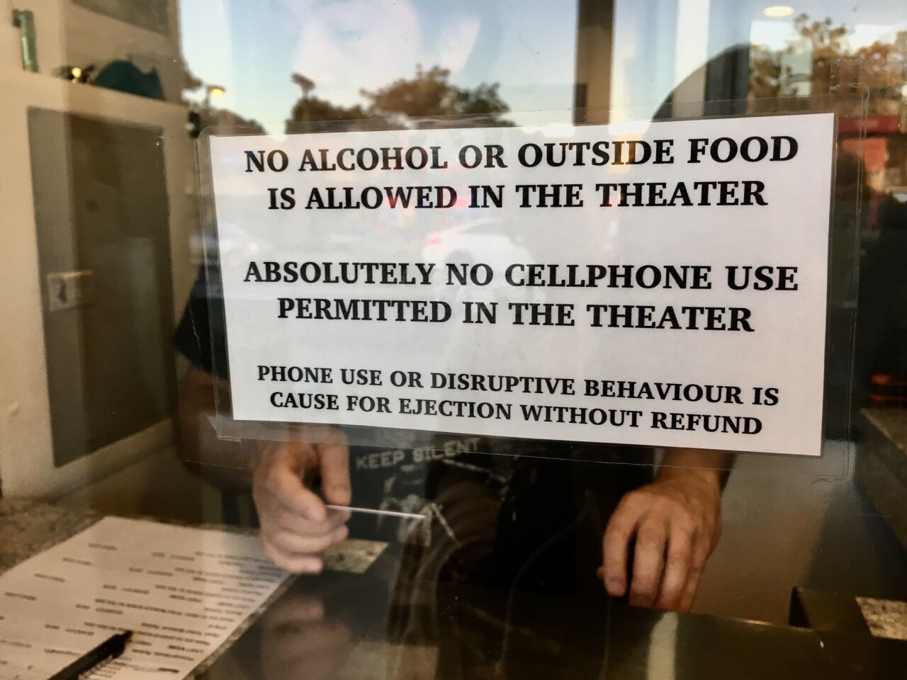 A sign on the New Beverly Cinema ticket window warns against disruptive moviegoing.