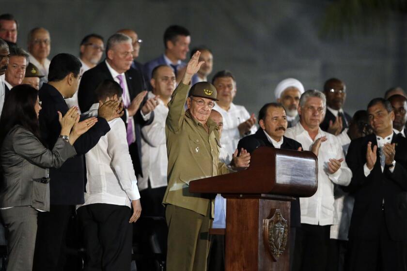 Cuba's President Raul Castro, center, salutes as he arrives at a rally honoring his brother Fidel Castro, who died Friday, at the Revolution Plaza in Havana Tuesday night.