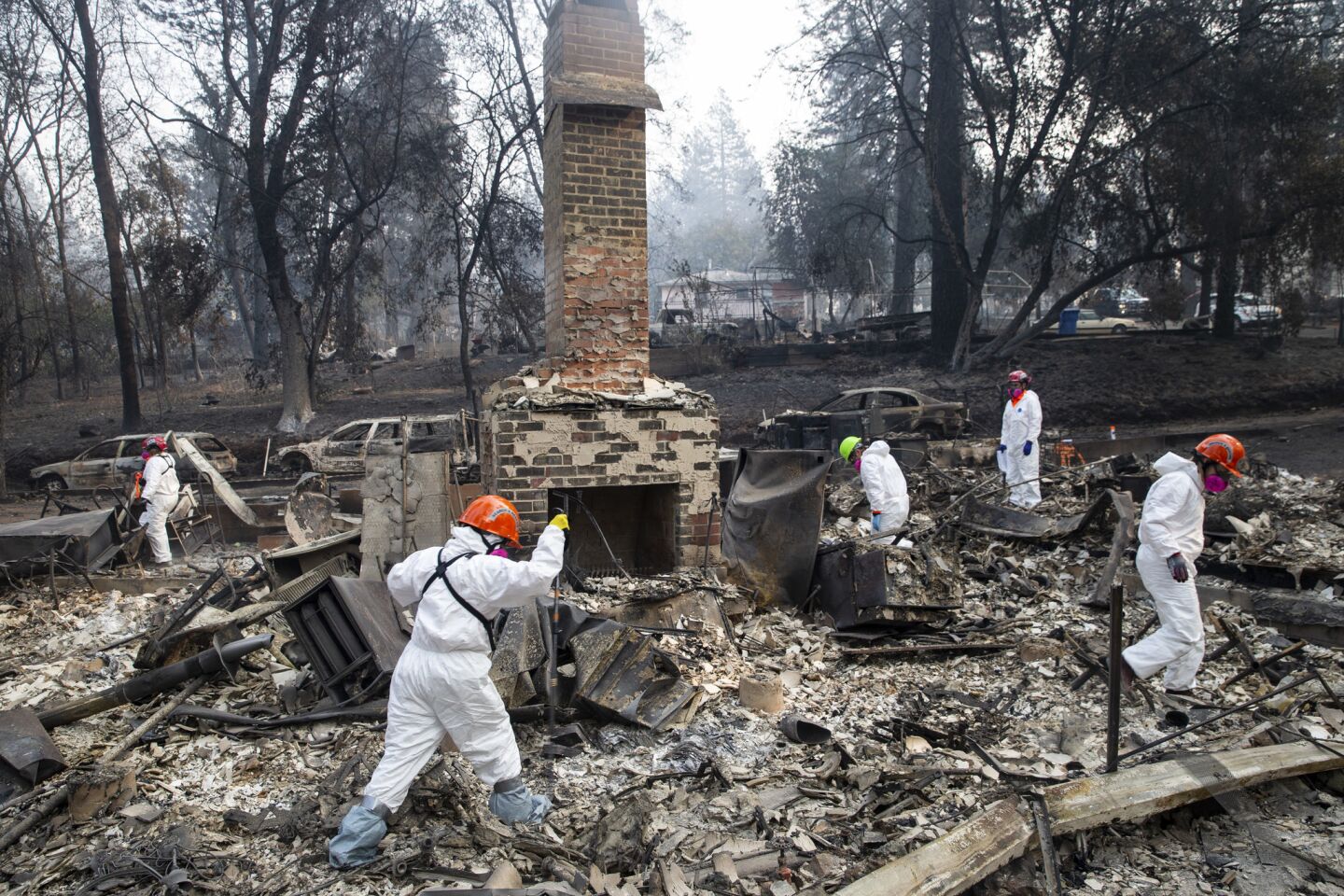 Search and rescue teams inspect the grounds of a house burned by the Camp Fire along Boquest Boulevard in Oroville, Calif.