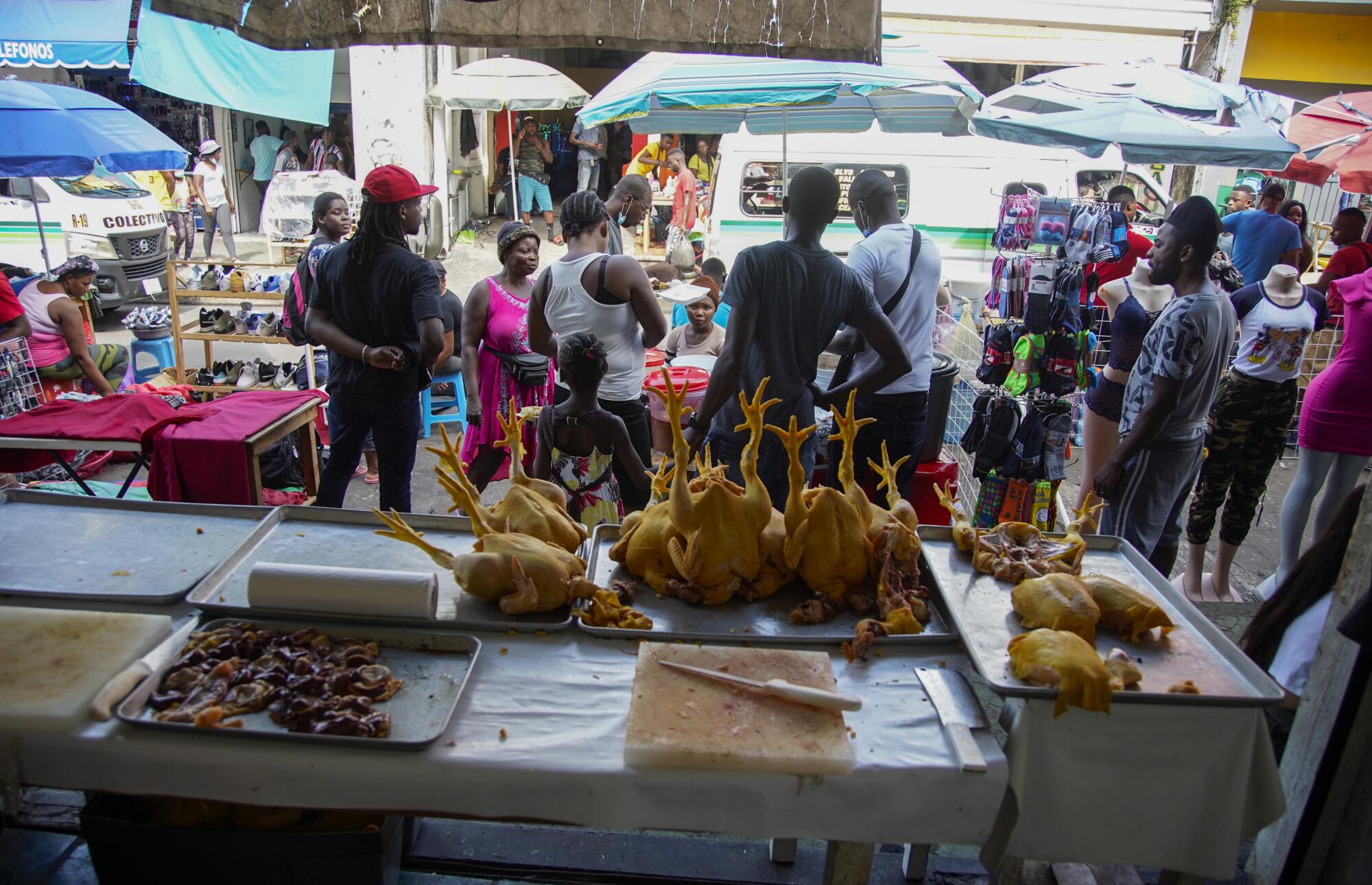 Haitian street vendors sell goods near a chicken stand