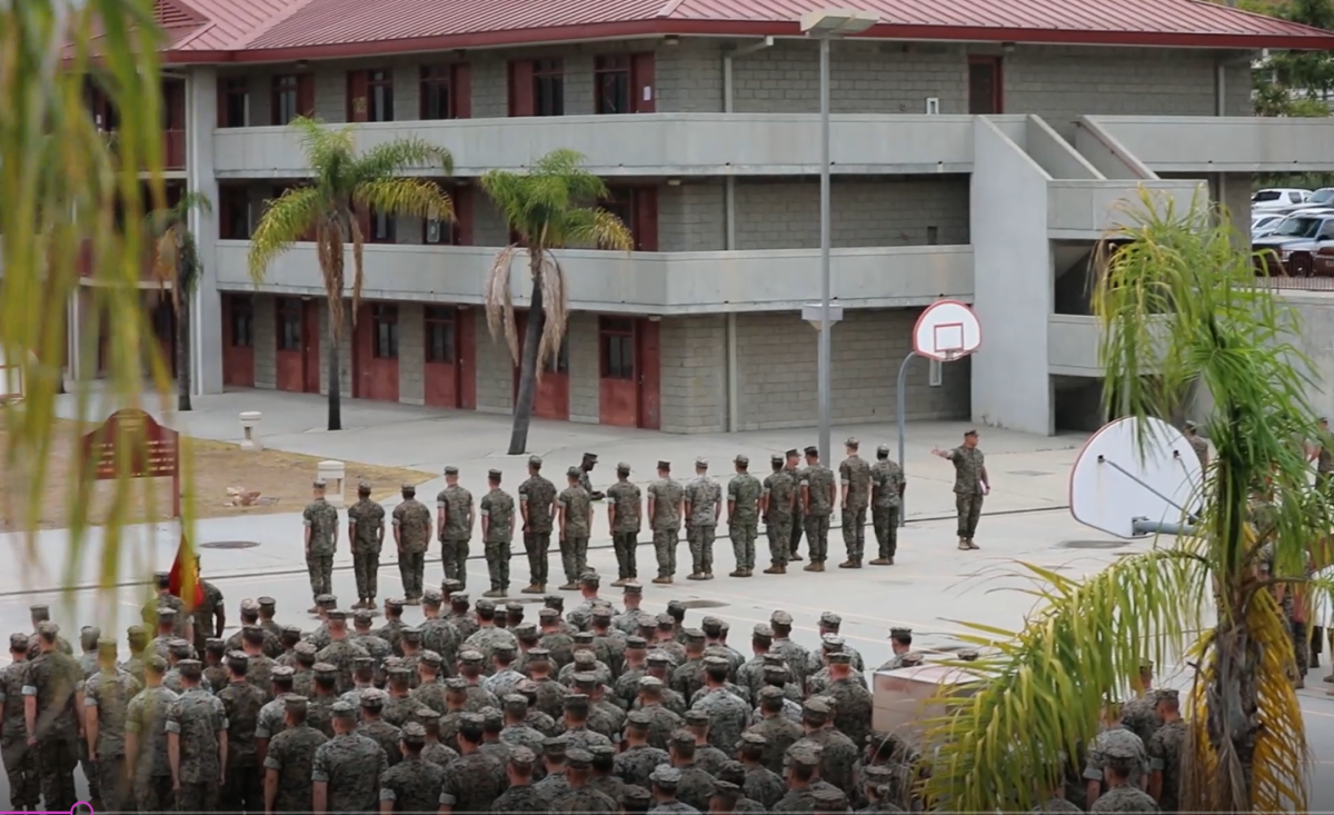 In this video screenshot, the battalion sergeant major for 1st Battalion, 5th Marine Regiment , Sgt. Major Matthew Dorsey, points at a line of 15 Marines as he instructs waiting NCIS agents to arrest them.