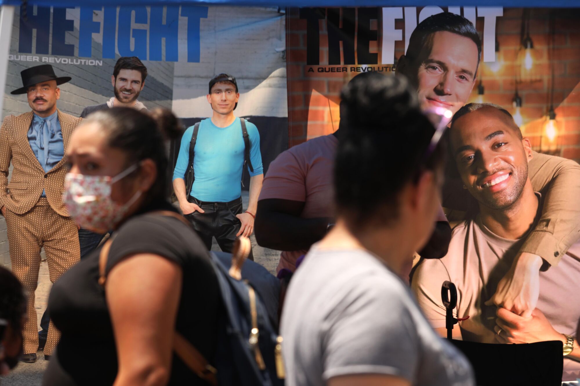 Shoppers walk past the Queer Mercado booth for the Fight magazine.