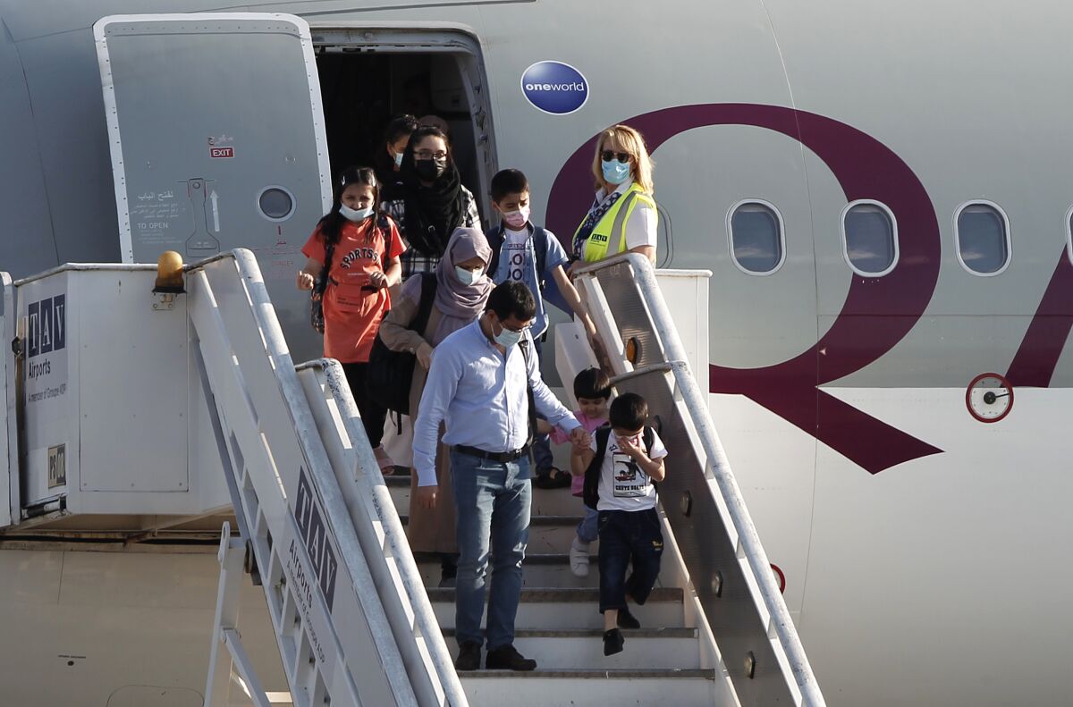 Afghan evacuees disembark the plane to board a bus after landing at Skopje International Airport, North Macedonia, on Wednesday, Sept. 15, 2021. North Macedonia has hosted another group of 44 Afghan evacuees on Wednesday where they will be sheltered temporarily till their transfer to final destinations. (AP Photo/Boris Grdanoski)