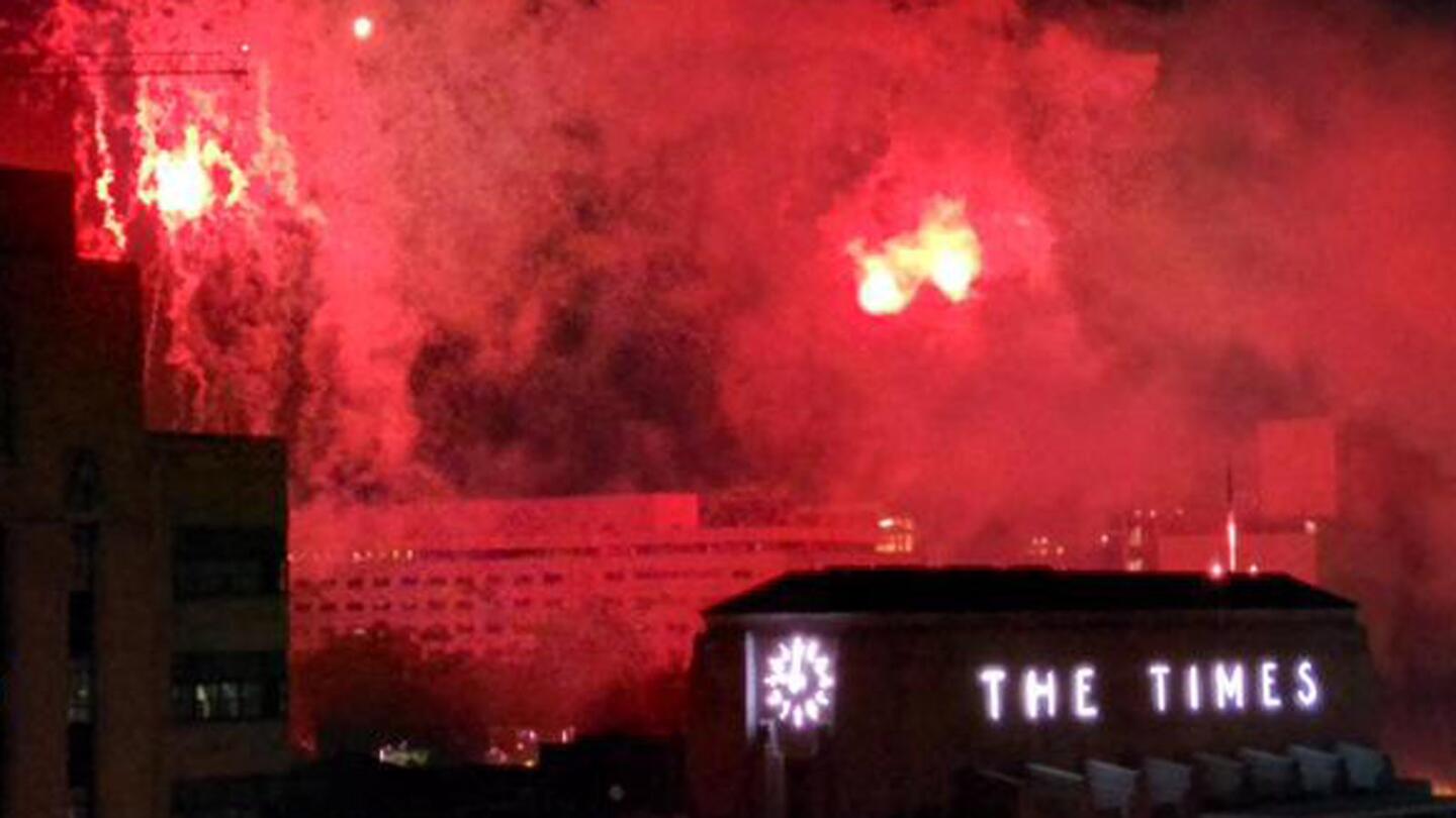 Fireworks bathe downtown buildings in a red glow.