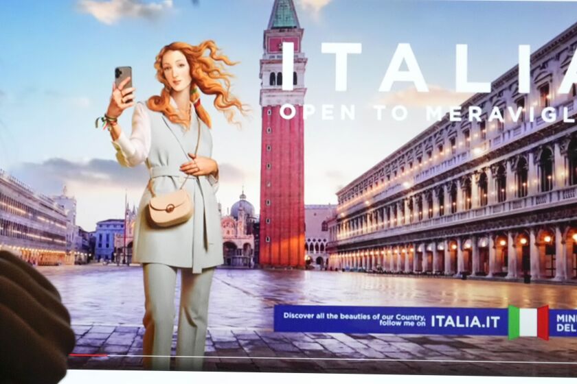 Unas personas observan un monitor con una campaña publicitaria del Ministerio de Turismo de Italia que muestra una versión digitalizada, y vestida, de la Venus del pintor renacentista Sandro-Botticelli, en Florencia. (AP Foto/Gregorio Borgia)