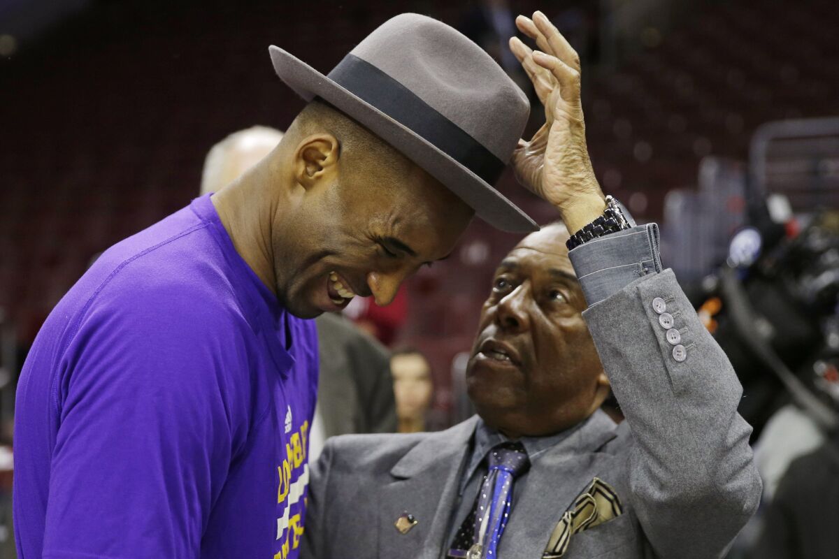 Lakers forward Kobe Bryant laughs as Philadelphia basketball humitarian Sonny Hill places his hat on Bryant's head before a game against the 76ers.