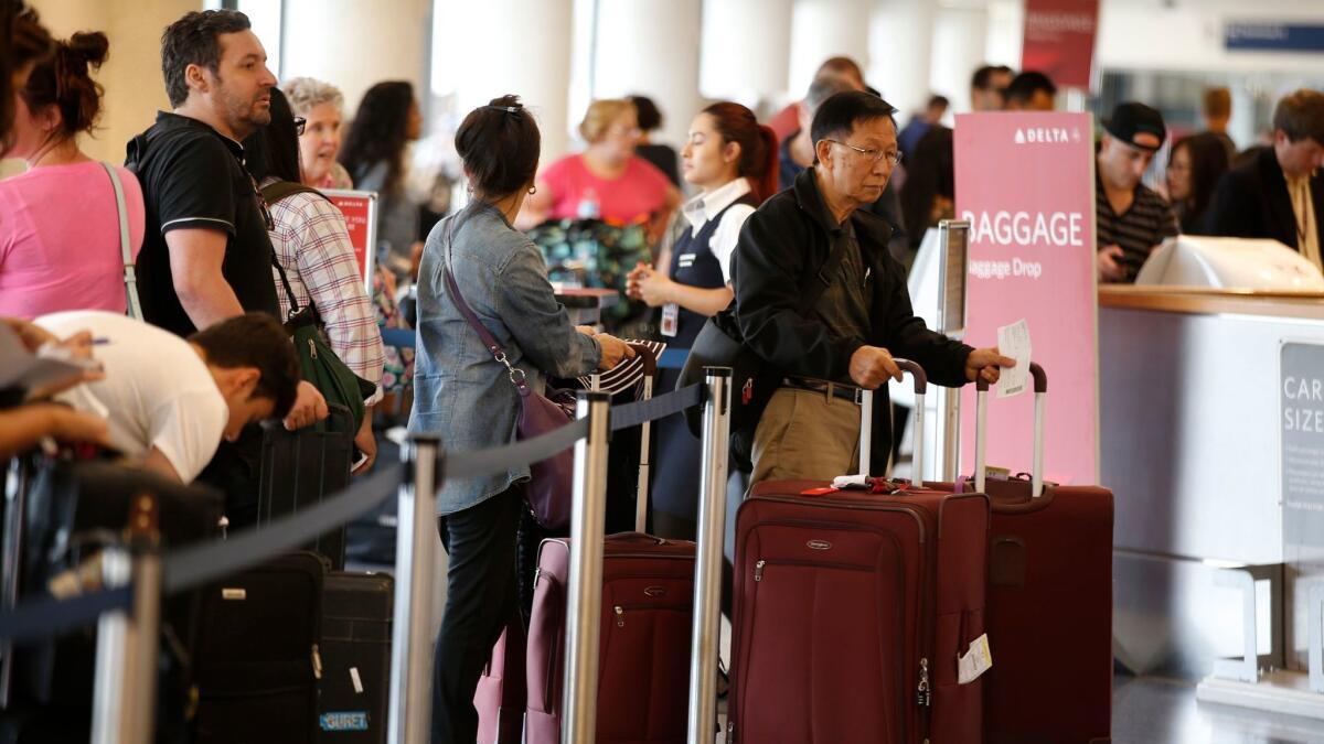 Travelers wait at the Delta Air Lines counter in Terminal 5 at Los Angeles International Airport.