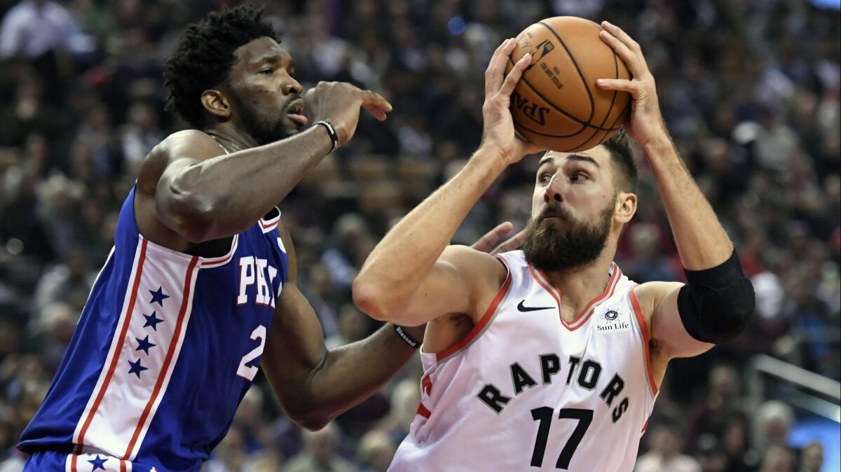 Toronto's Jonas Valanciunas is defended by Philadelphia's Joel Embiid.