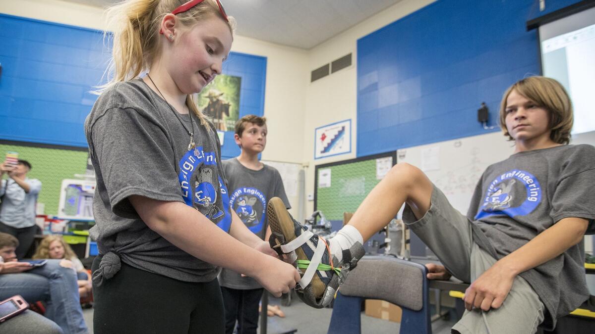 Kylie Papa, 12, demonstrates a foot brace on Tristen Stoll, 13, during the Ensign Intermediate School engineering program's inaugural showcase Wednesday evening.