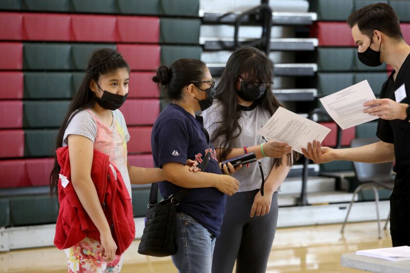 LOS ANGELES, CA - MAY 27: Estella Cornejo, 13, mother Guadalupe Cornejo and sister Guadalupe Cornejo, 14, register to get a COVID-19 vaccination at Esteban Torres High School on Thursday, May 27, 2021 in Los Angeles, CA. Governor Gavin Newsom unveils a $116.5 million COVID-19 vaccine incentive plan, including cash prizes and gift cards. New efforts by the state to encourage more Californians - especially those in communities that have been hit hardest by the pandemic - to get vaccinated. (Gary Coronado / Los Angeles Times)