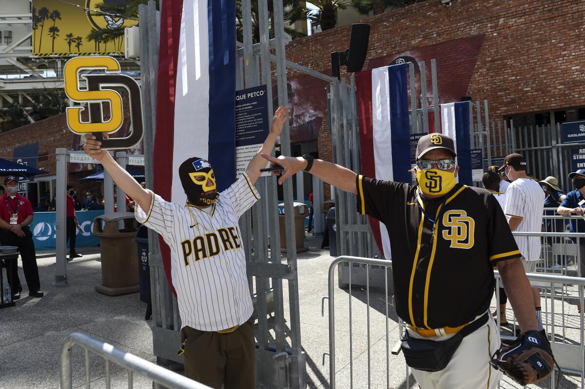 Baseball fans Mercury Hornbeek, left, and Steven Ames wait in line before the gates opened up before a baseball game between the Arizona Diamondbacks and the San Diego Padres Thursday, April 1, 2021, on opening day in San Diego. (AP Photo/Denis Poroy)