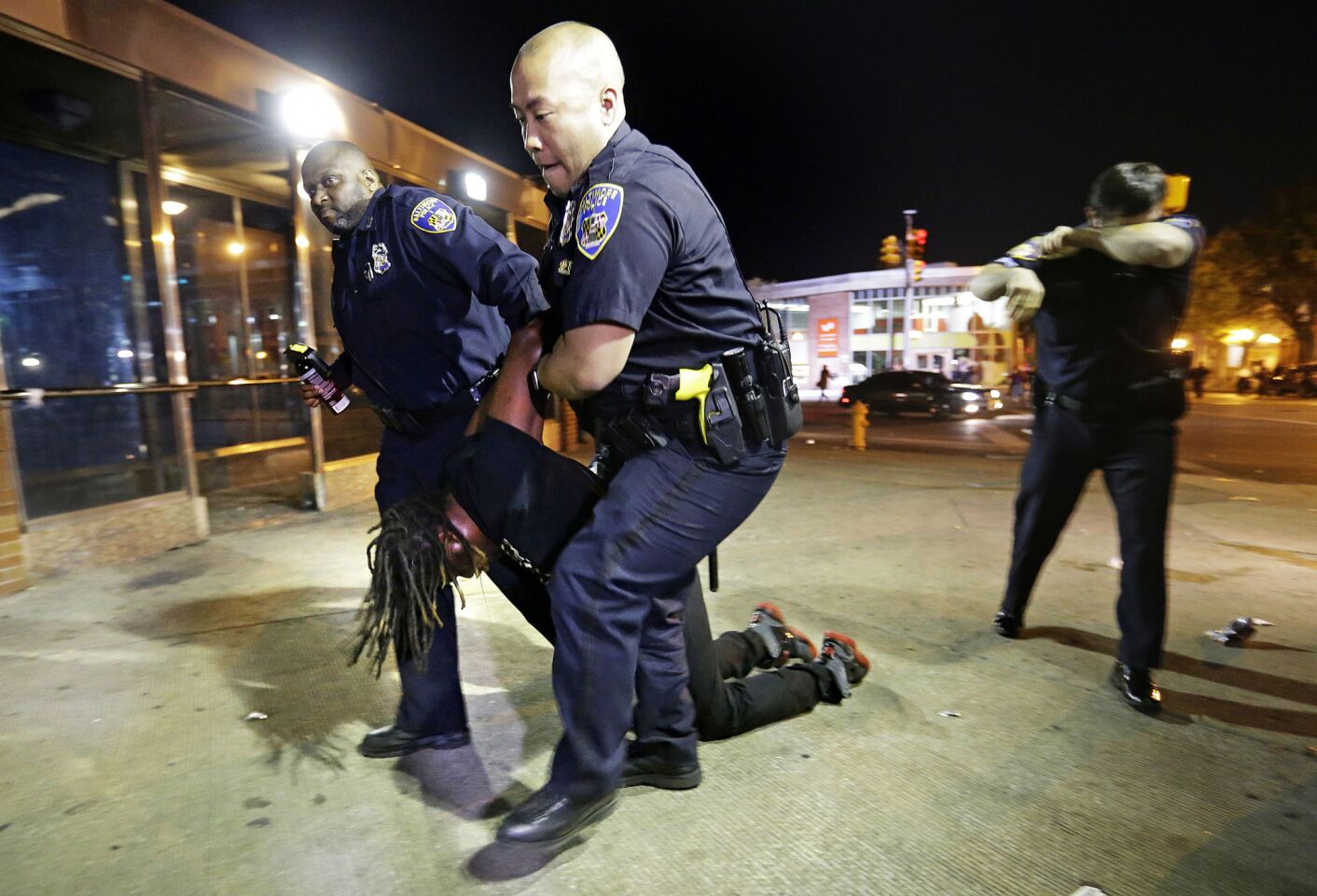 Police carry a man after he was arrested and hit with pepper spray as officers enforced a 10 p.m. curfew Saturday in Baltimore.