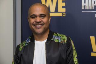 Irv Gotti smiles in a white t-shirt and a black embellished bomber jacket