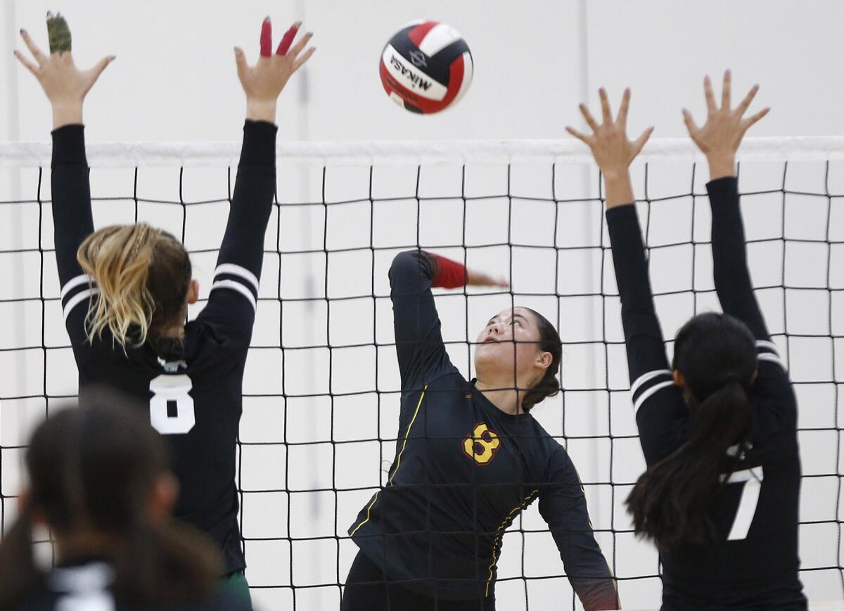 Estancia's Leila Sanchez (8) kills a ball past the block of Costa Mesa's Lucca Miller (8) Aubrey Spallone (7) on Tuesday.