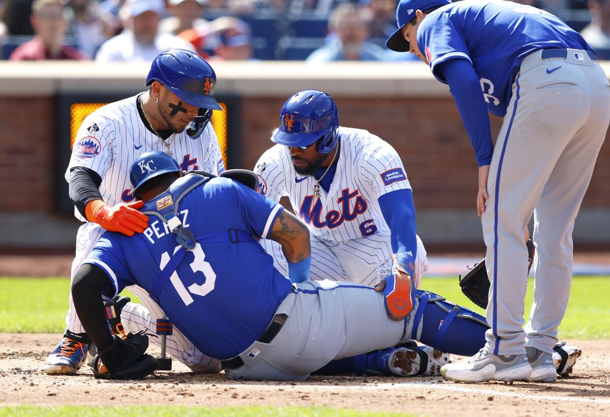 New York Mets' Francisco Alvarez and Starling Marte help Kansas City Royals catcher Salvador Perez (13) who injured on a play at the plate during the fourth inning of a baseball game, Sunday, April 14, 2024, in New York. (AP Photo/Noah K. Murray)