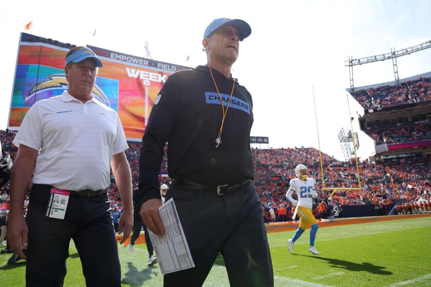 Chargers coach Jim Harbaugh walks onto Empower Field At Mile High before their game against the Denver Broncos.