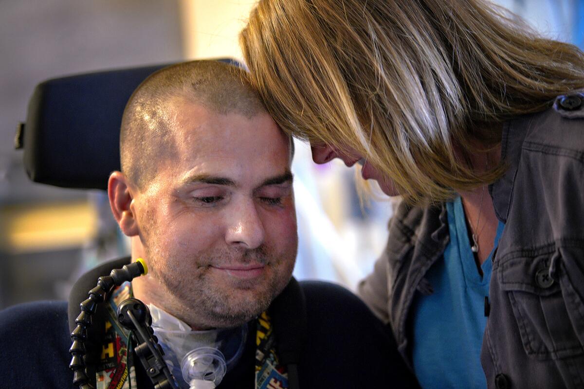 During a recent hospital visit, the couple enjoys a brief quiet moment together in the presence of nurses and a physical therapist. Lindsey Stacy visits her husband, Kenton, at the VA Medical Center in La Jolla, Calif., twice a day and cares for the couple's four children.